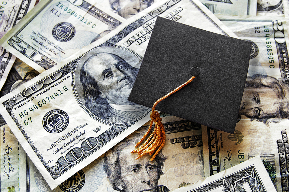 Graduation cap on a pile of $100 bills