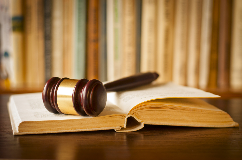 gavel on an open book in front of bookshelf