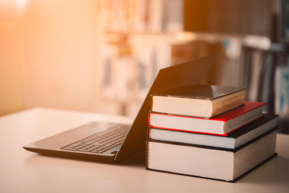 laptop next to stack of books