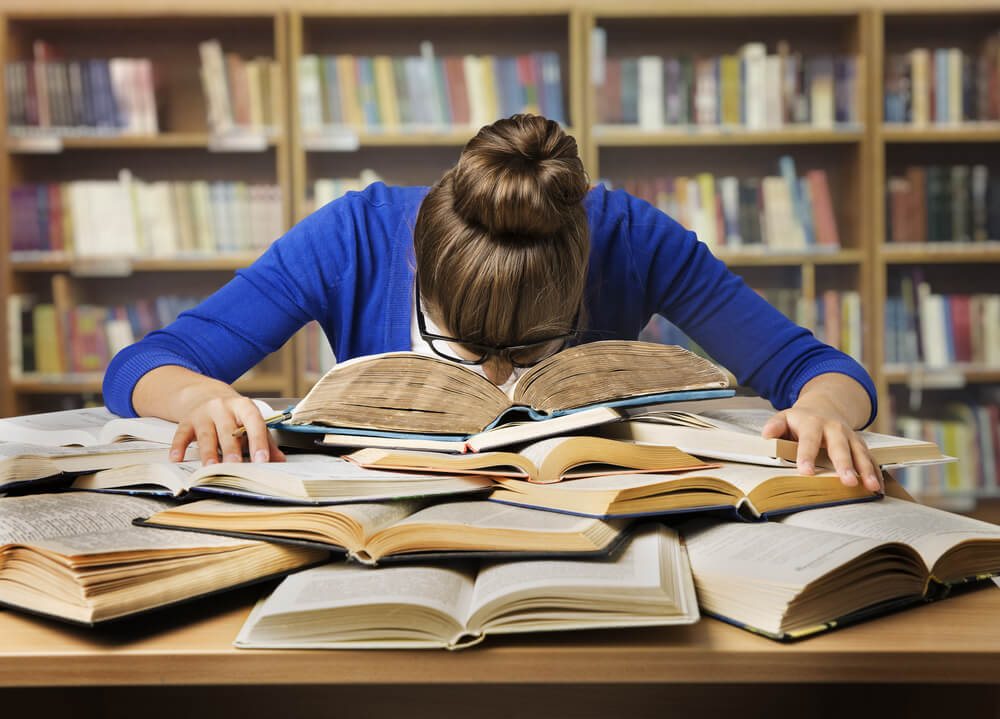 student sleeping on textbooks