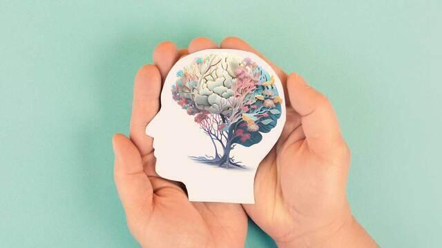 Hands holding a paper cutout of a head with a brain illustration