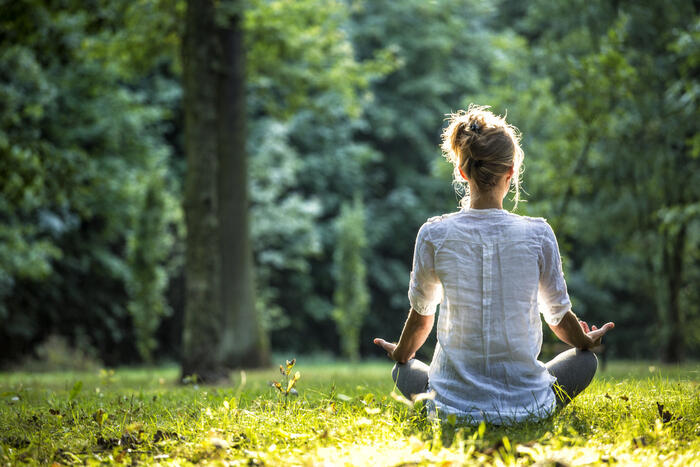 Young woman meditating in a green field