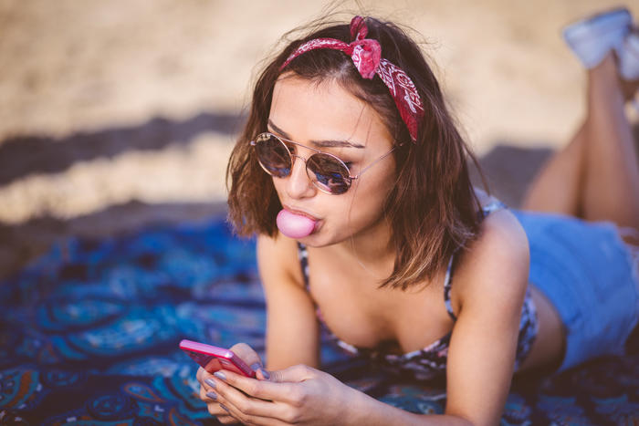 Girl chewing gum looking at phone